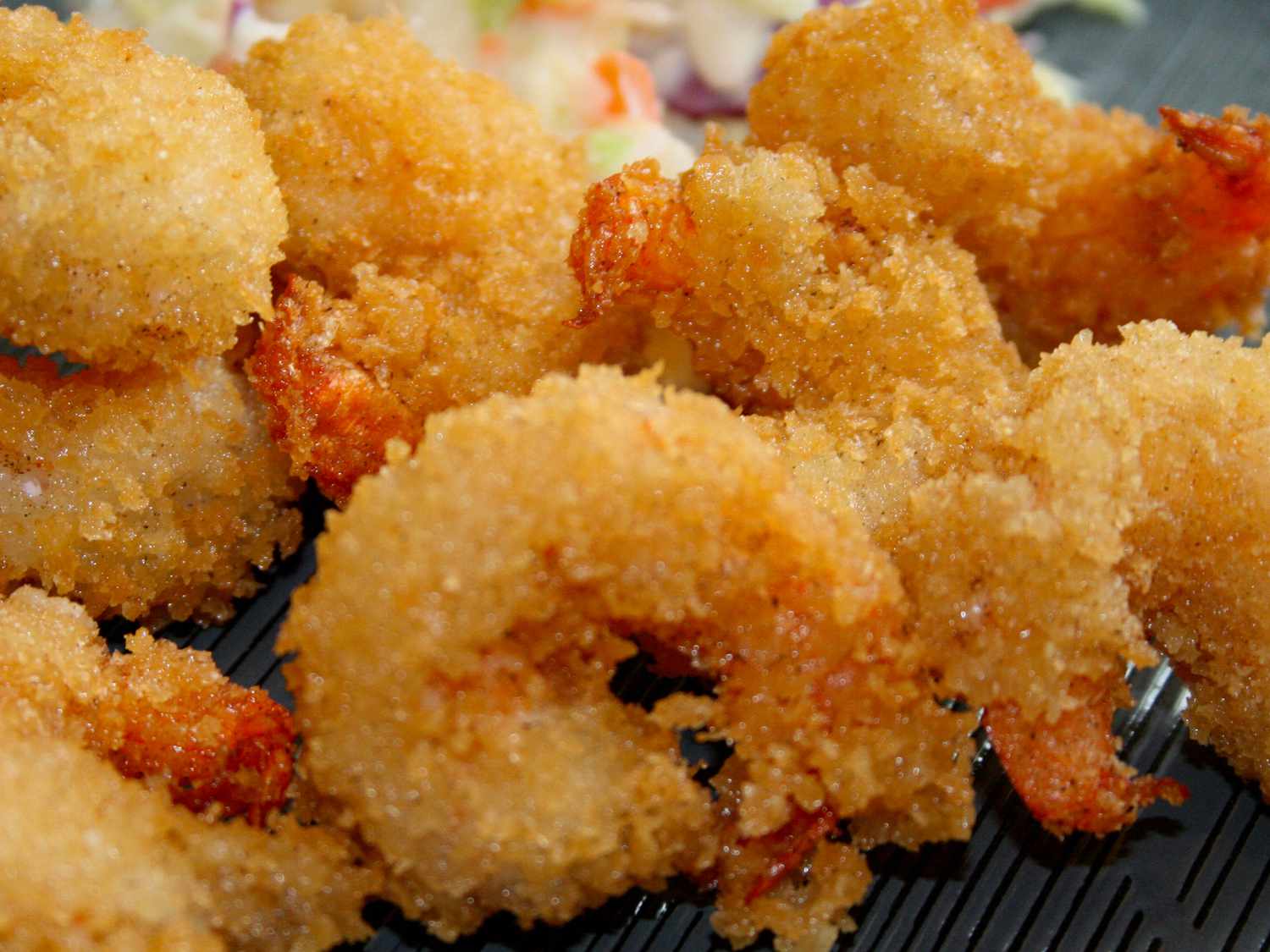 close up view of Fried Butterflied Shrimp on a black plate