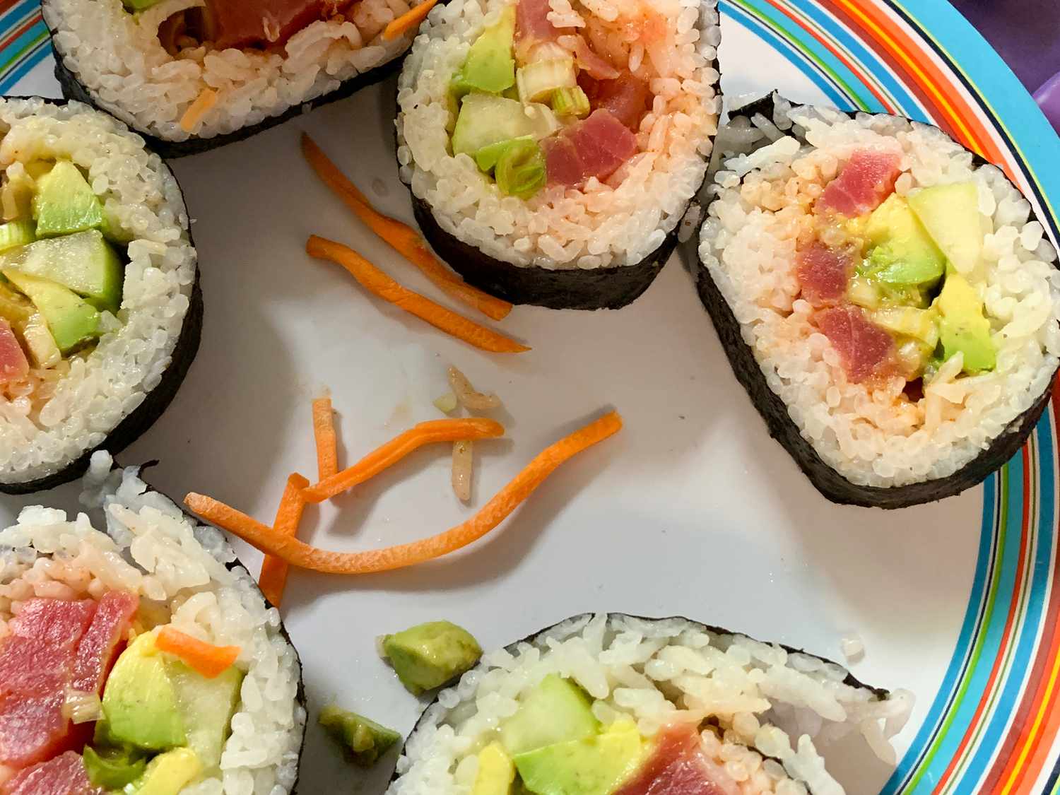 close up view of Spicy Tuna Sushi Roll pieces on a plate with carrot pieces
