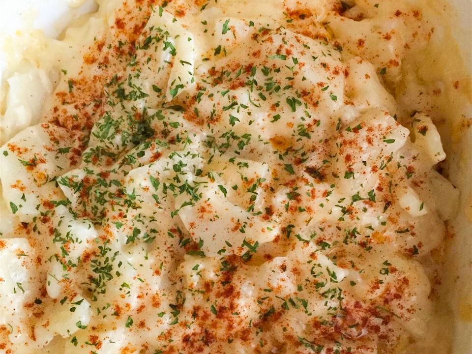 close up view of Microwave Scalloped Potatoes garnished with paprika and herbs in a bowl