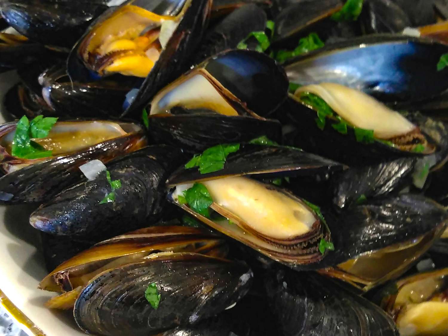 close up view of Mussels Mariniere garnished with fresh herbs in a bowl