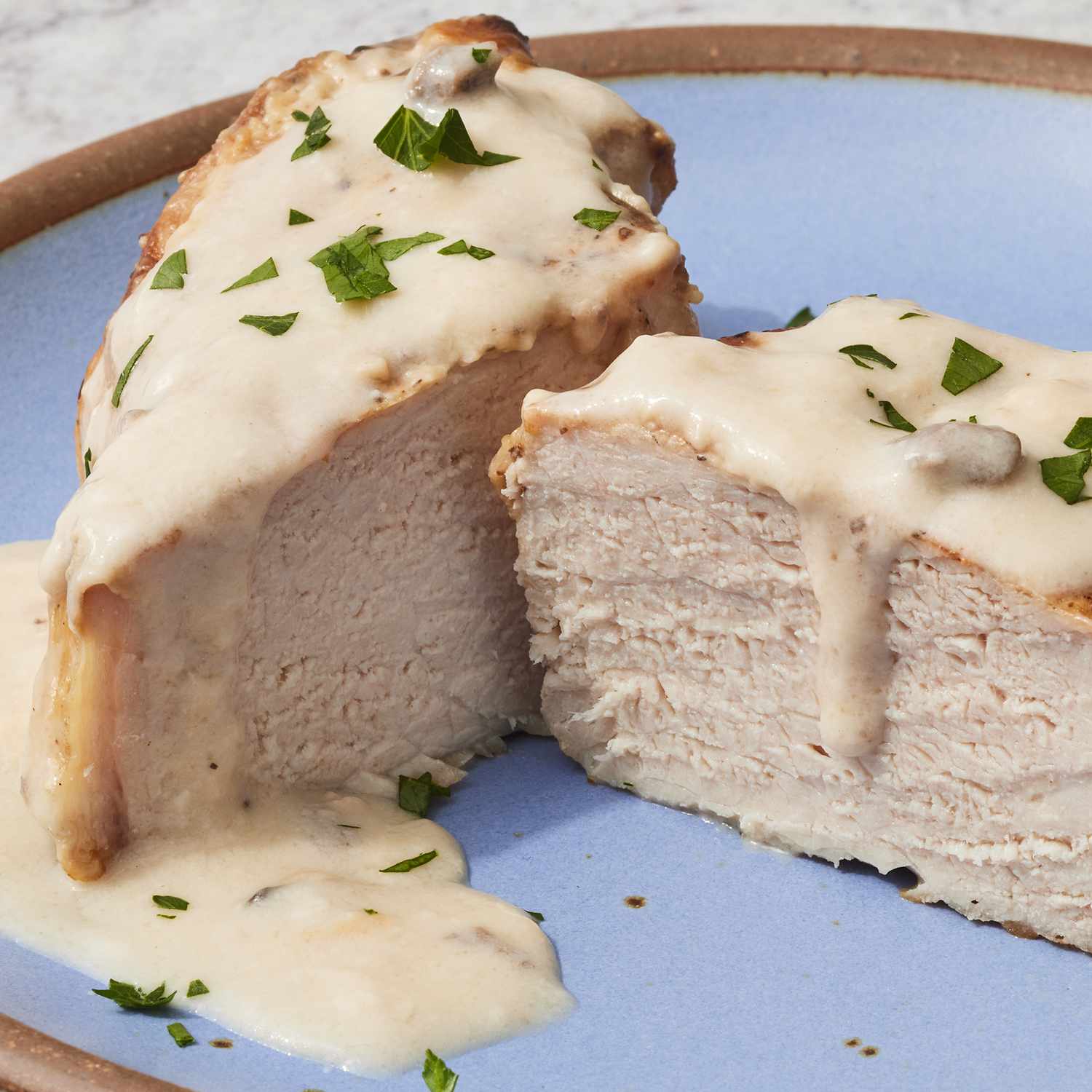 high angle looking at gravy baked pork chops cut in half with gravy dripping down