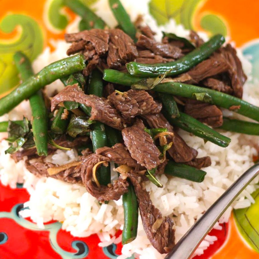 close up view of Thai Beef with green beans over white rice on a colorful plate