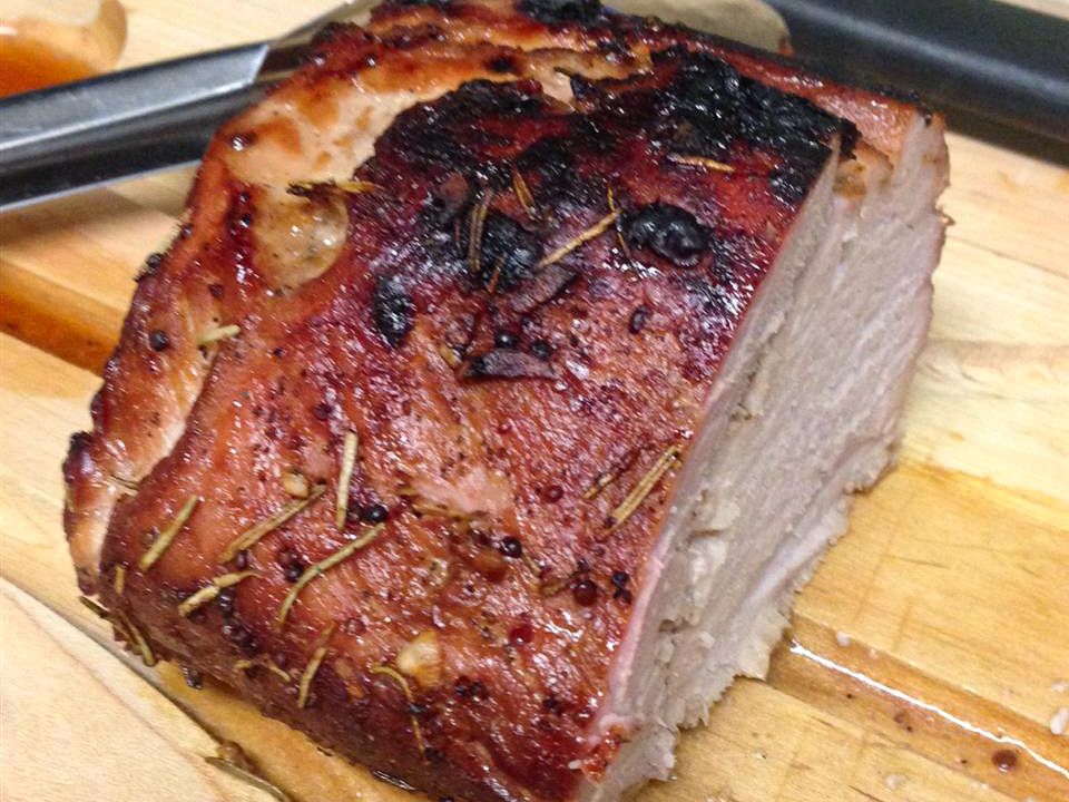 close up view of Orange Marinated Pork Tenderloin on a wooden cutting boar with tongs
