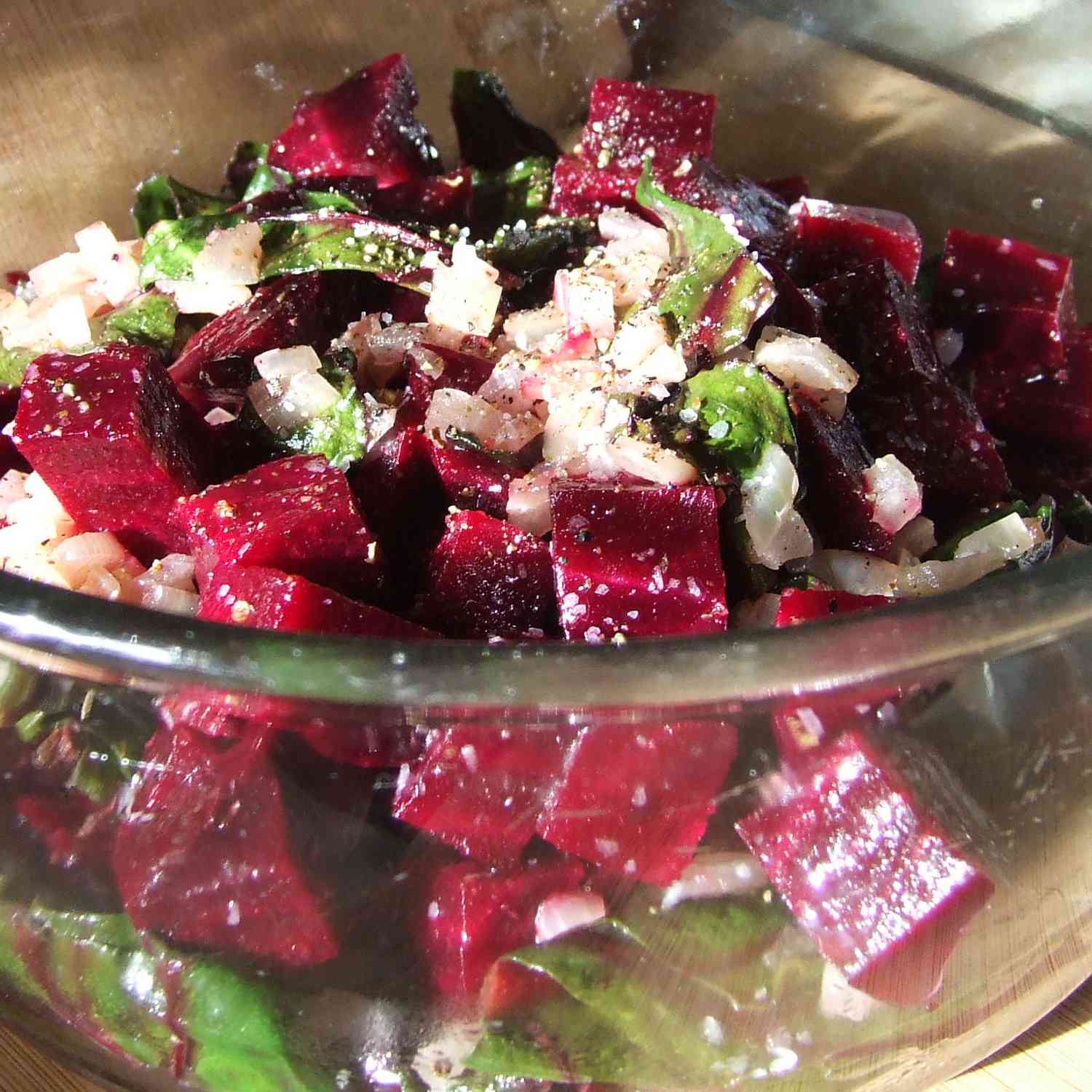 close up view of Roasted Beets and Sauteed Beet Greens with onions in a glass bowl