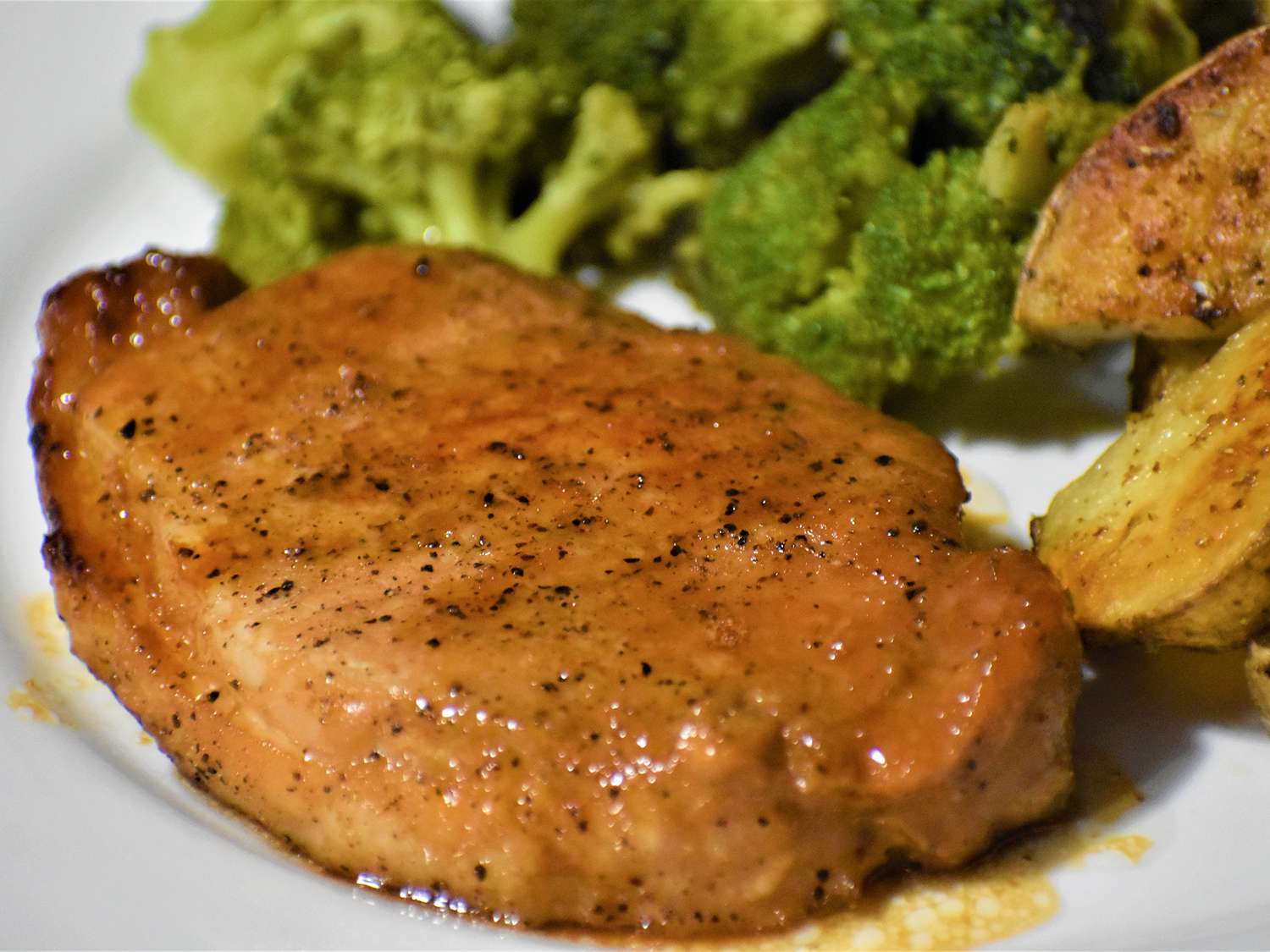 close up view of a Honey-Garlic Pork Chop served with broccoli on a plate