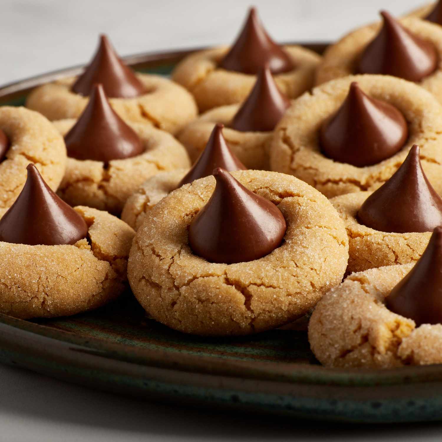 a low angle, close up view of a plate full of peanut butter cookies topped with a chocolate kiss