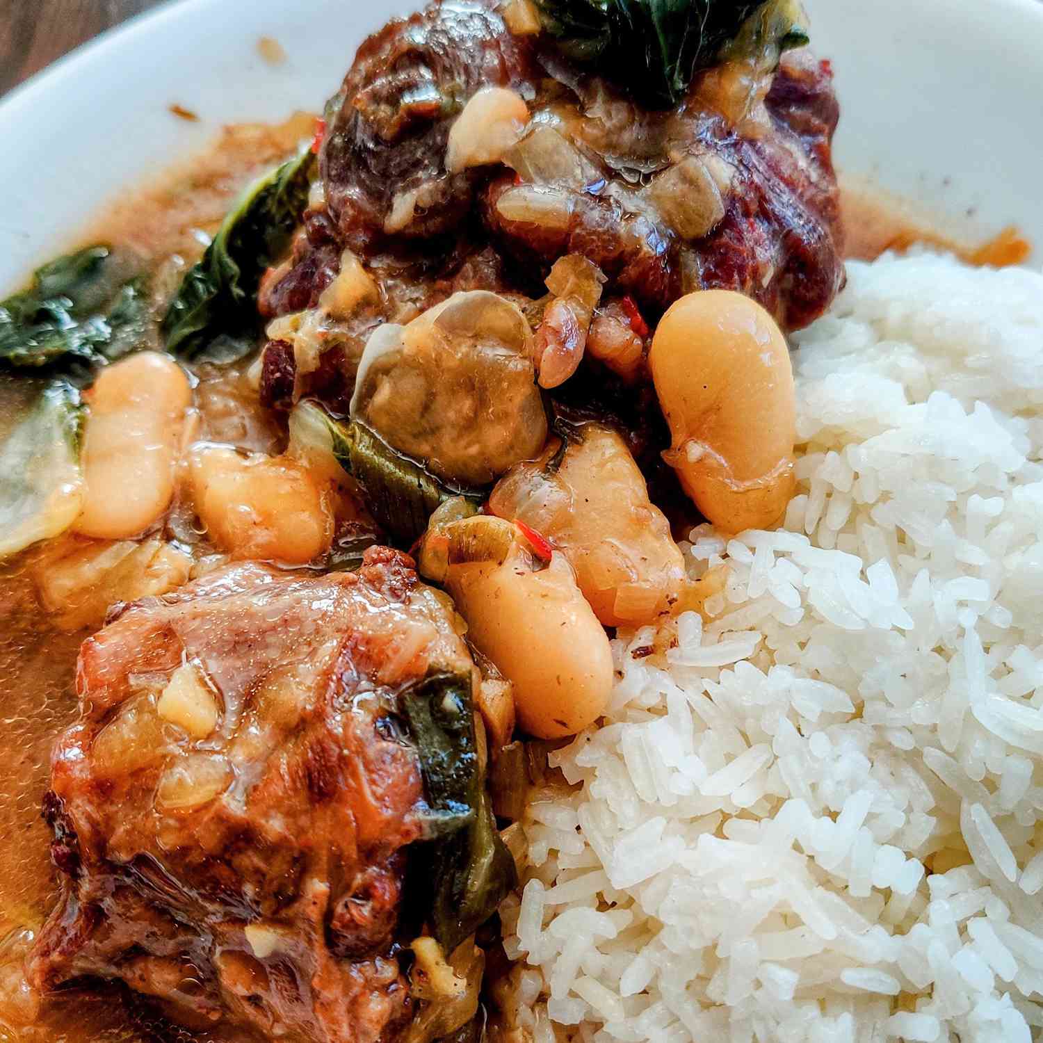 close up view of Jamaican Oxtail with Broad Beans served with white rice on a plate