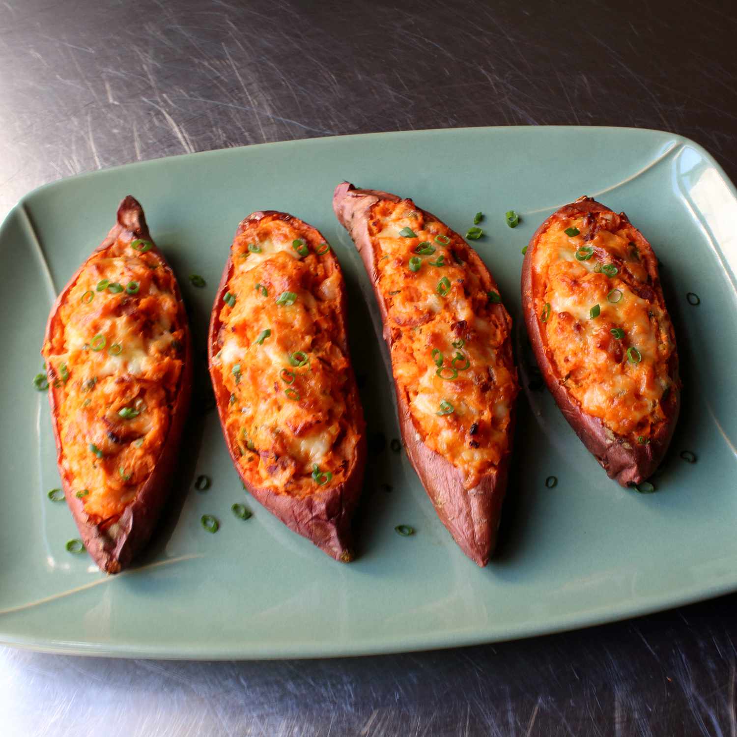 close up view of Loaded Twice-Baked Sweet Potatoes garnished with green onions on a platter