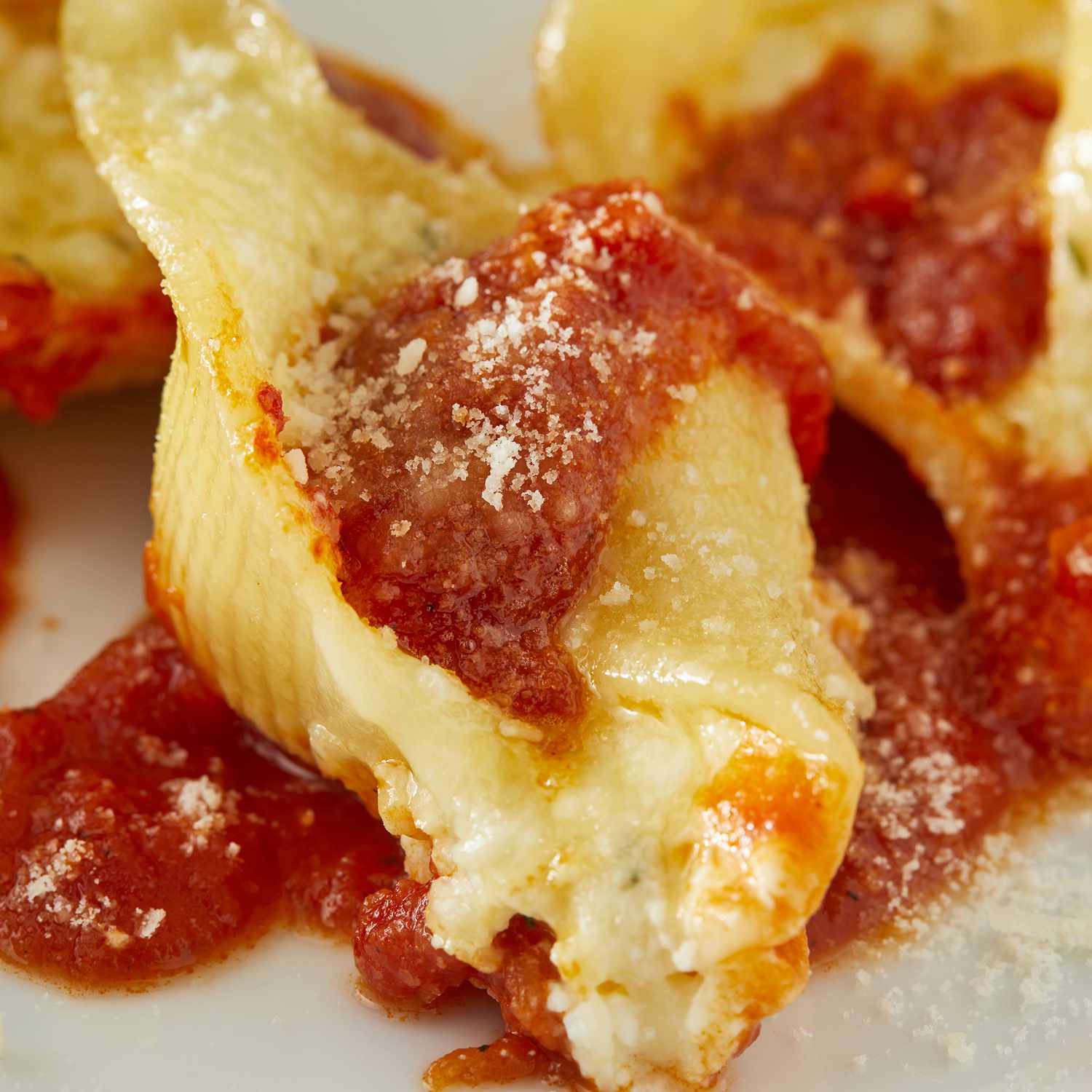 mid angle looking at a single stuffed shell topped with sauce and parmesan cheese