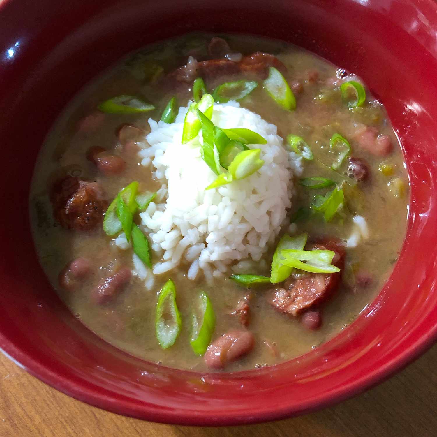 close up view of Red Beans and Rice garnished with green beans in a red bowl