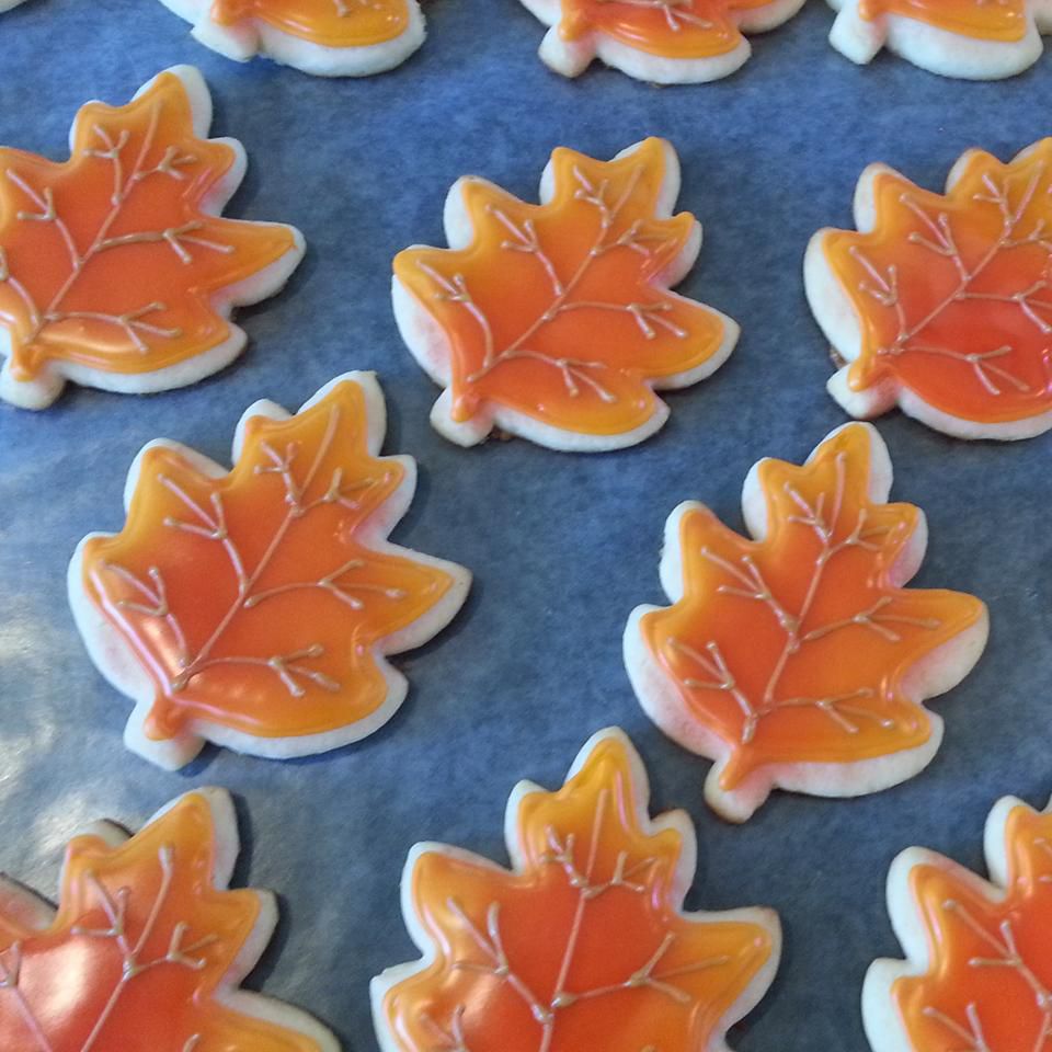 fall leaf-shaped cookies with yellow-orange icing piped with pale brown "veins"