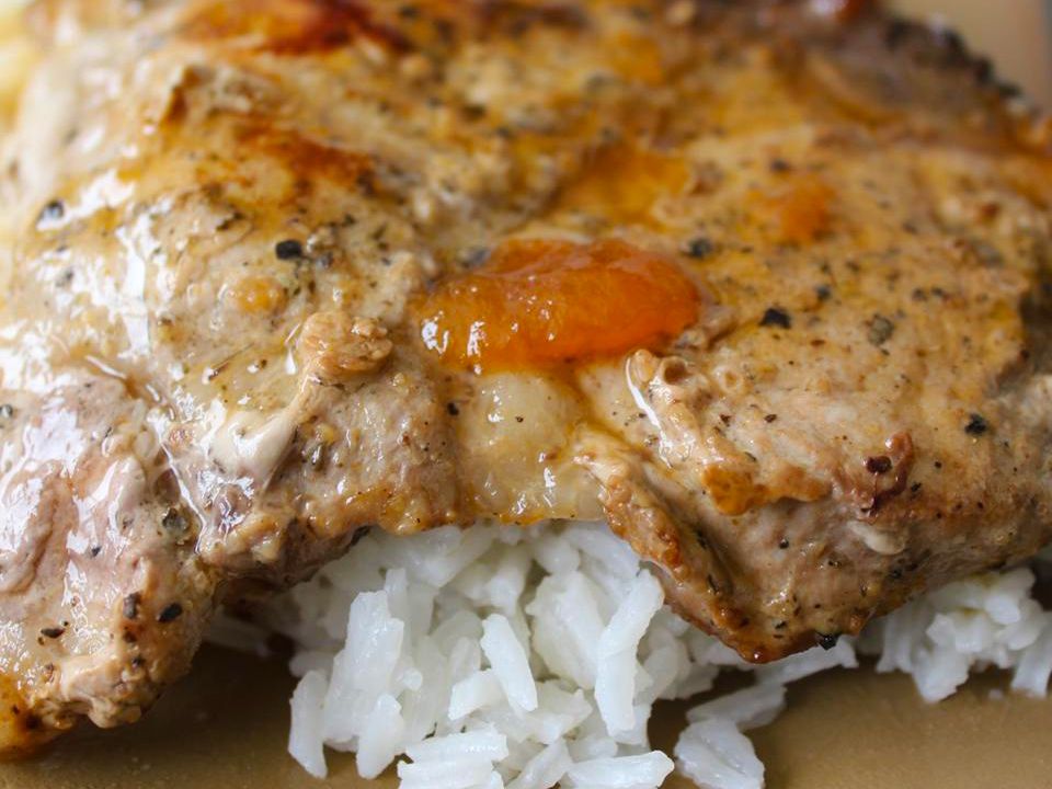 close up view of a Apricot-Glazed Pork Chop over white rice on a plate