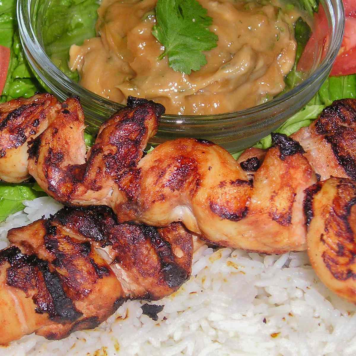 close up view of Indonesian Satay served with white rice and sauce with fresh herbs