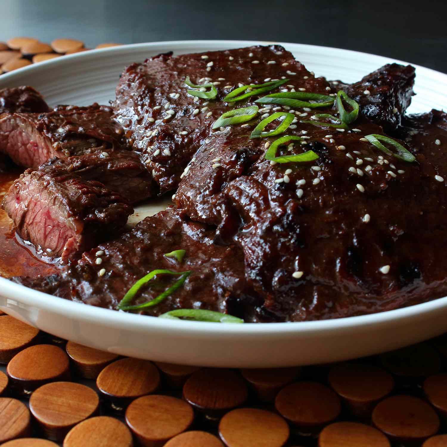 close up view of Grilled Hoisin Beef garnished with fresh herbs in a white bowl