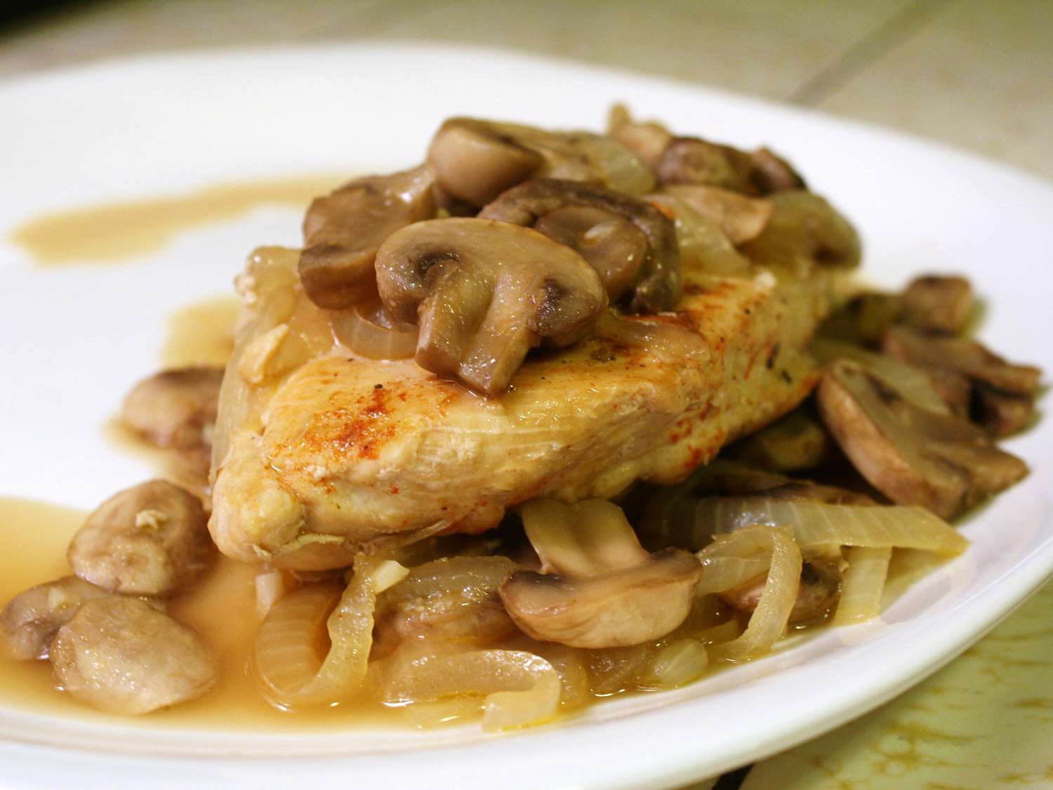 close up view of Paprika Chicken with Mushrooms and onions on a white plate