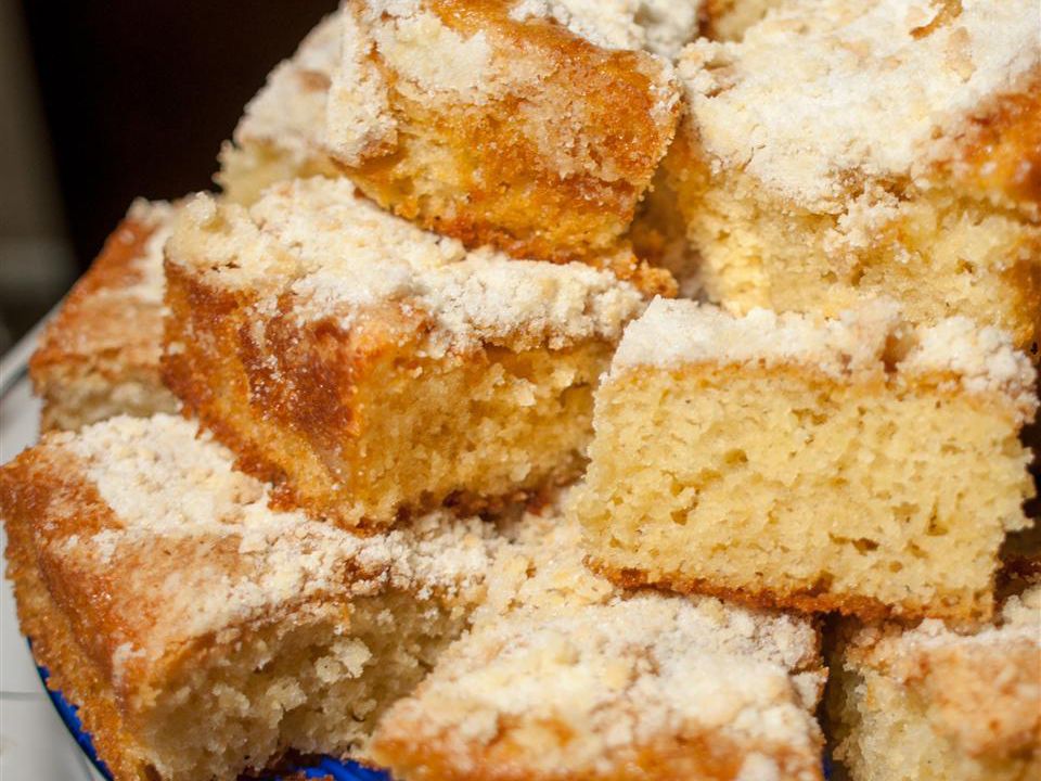 close up view of a pile of slices of Simple Buttermilk Coffee Cake garnished with powdered sugar on a platter