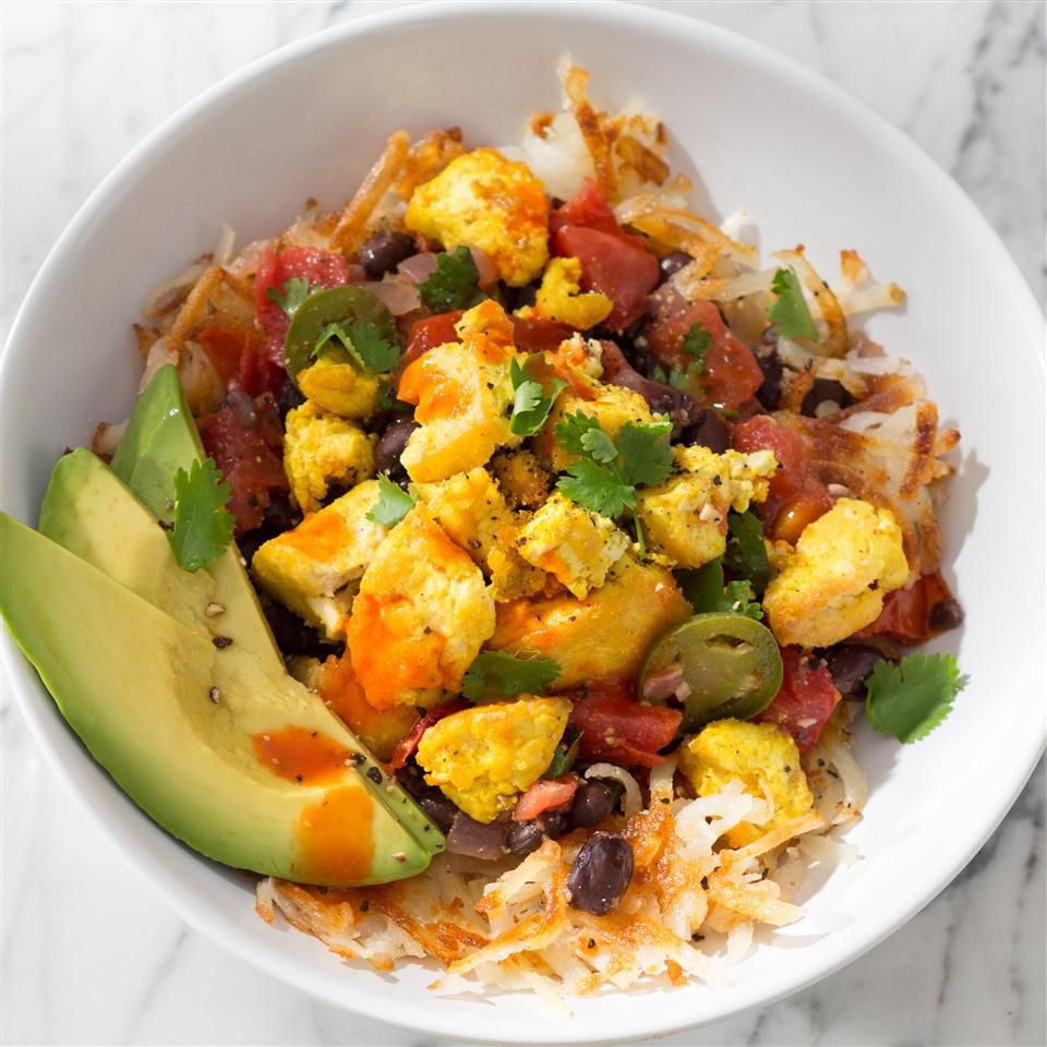 close up view of a Tofu Breakfast Burrito Bowl with avocado and hot sauce in a white bowl