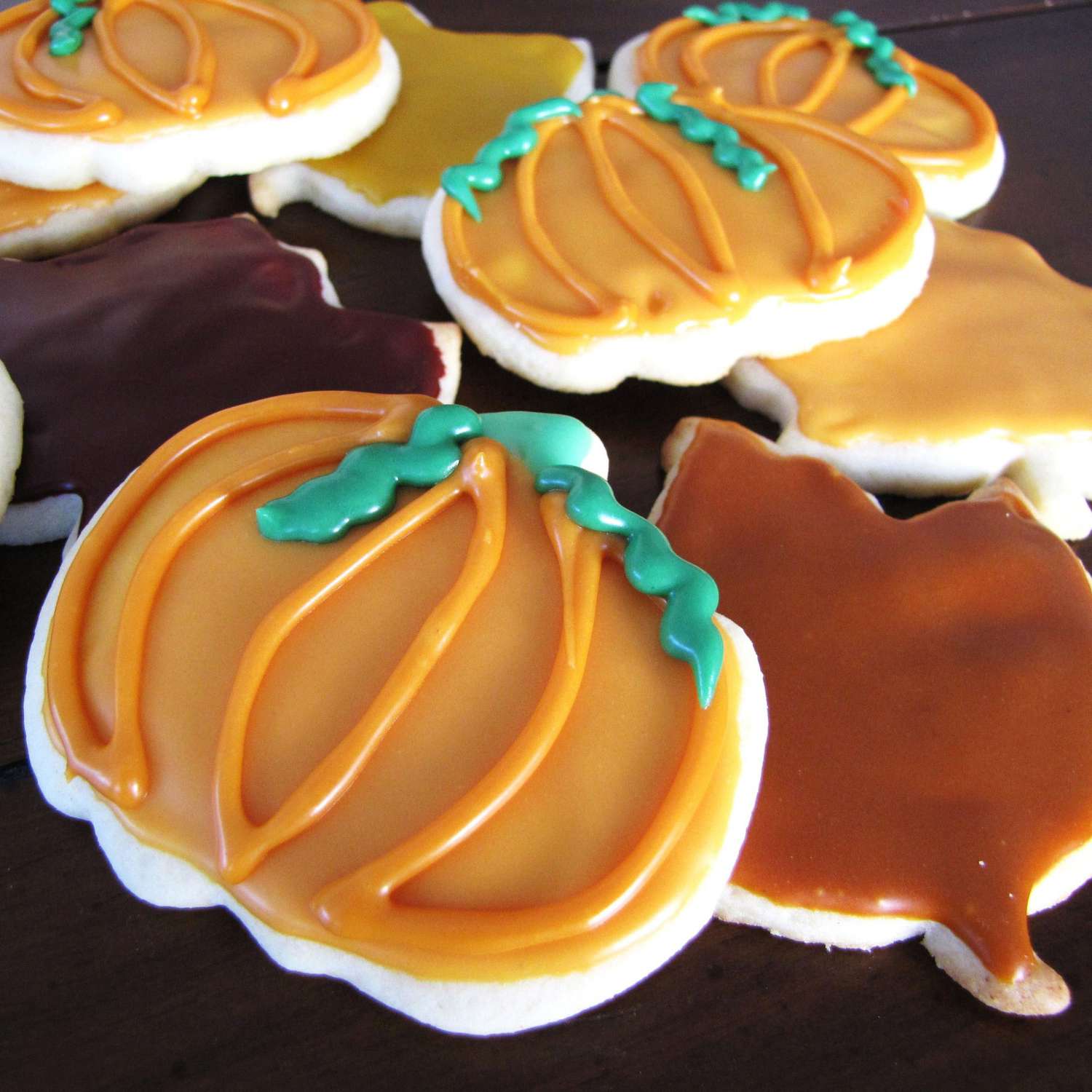 cookies decorated for fall: orange pumpkins with curly green vines and brown maple leaves