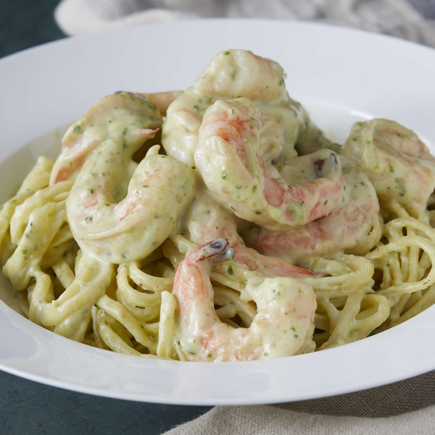 mid angle looking at a bowl of creamy pesto shrimp served over pasta