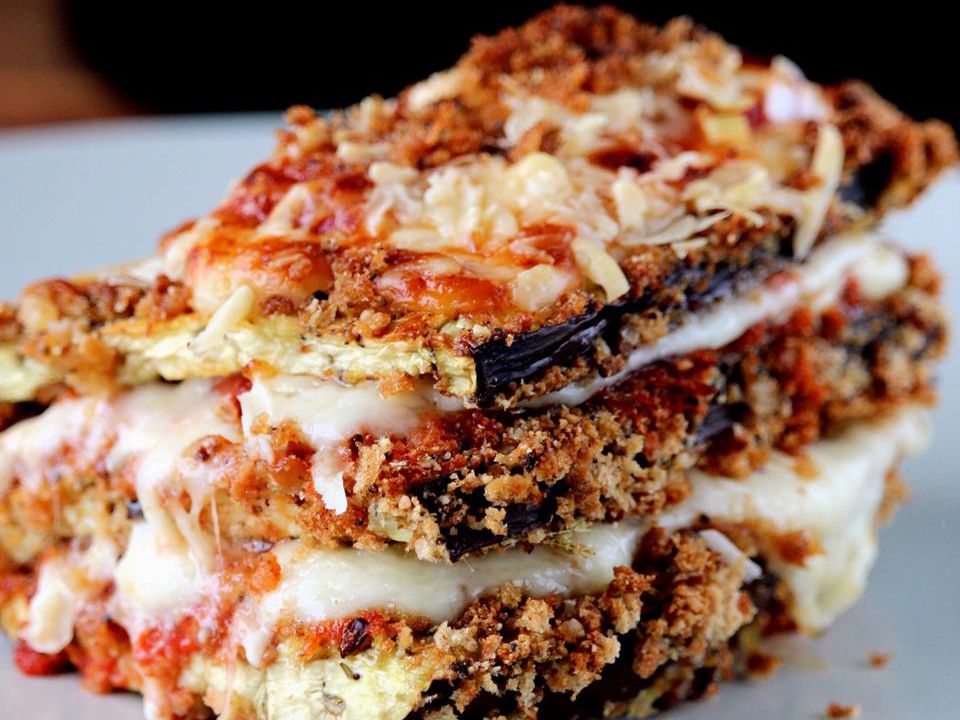 close up view of a slice of Eggplant Parmesan on a white plate