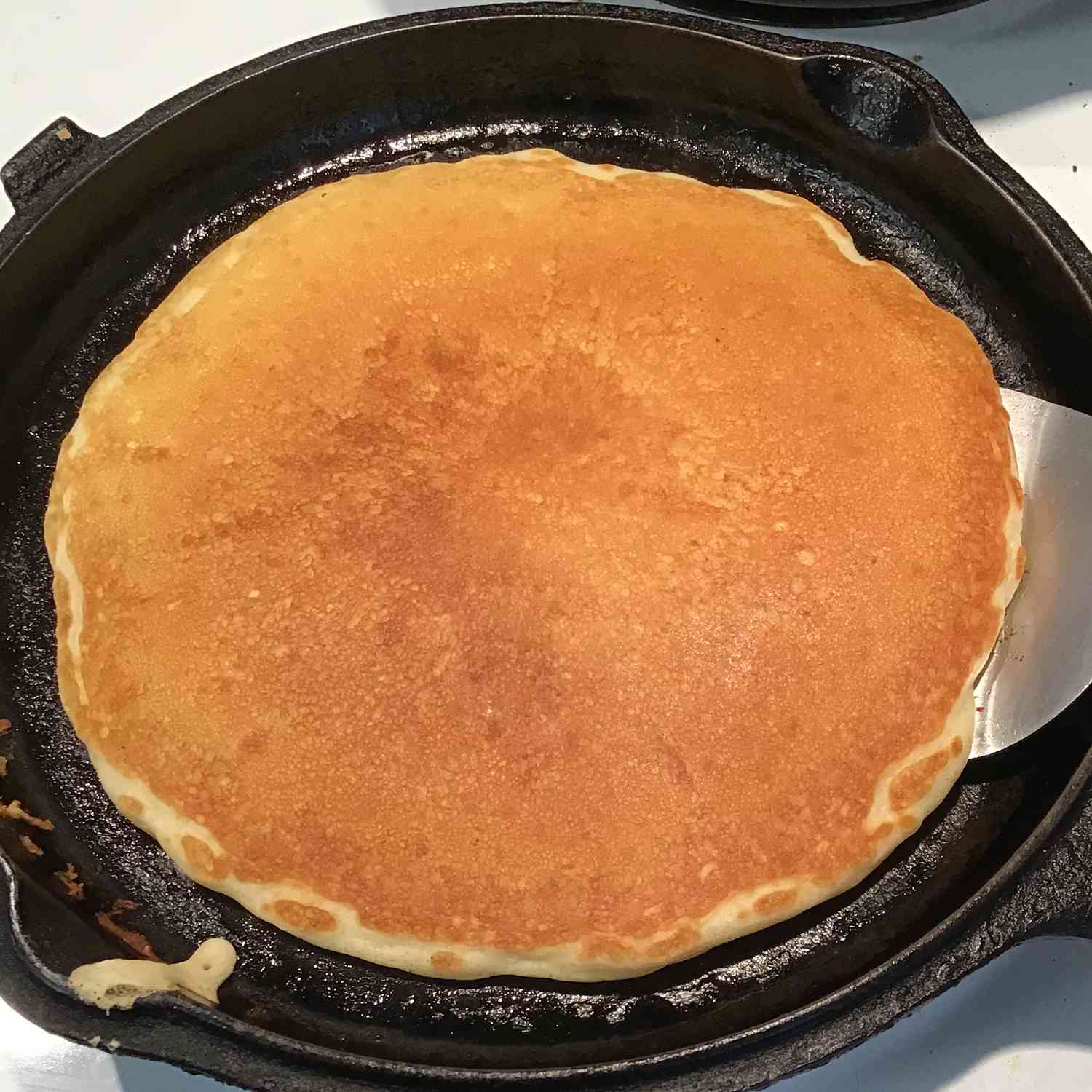 top-down view of a big golden-brown pancake in a cast-iron skillet