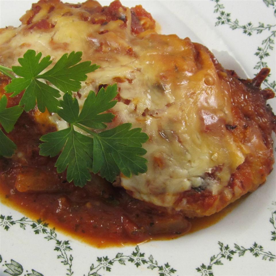 a serving of cheese-topped eggplant parm in a bowl garnished with a parsley sprig