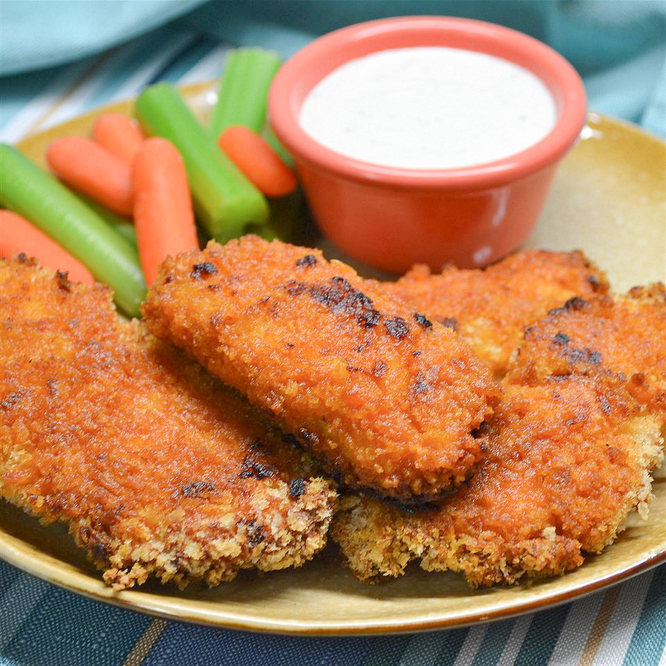 close up view of Buffalo Chicken Fingers served with carrots, celery, and white sauce in a red sauce cup
