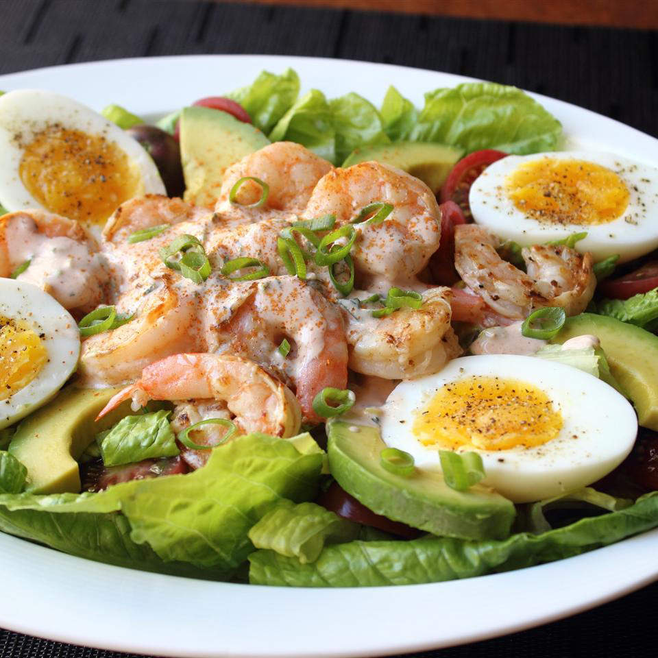 close up of a Grilled Shrimp salad with eggs, avocados, and lettuce in a white bowl