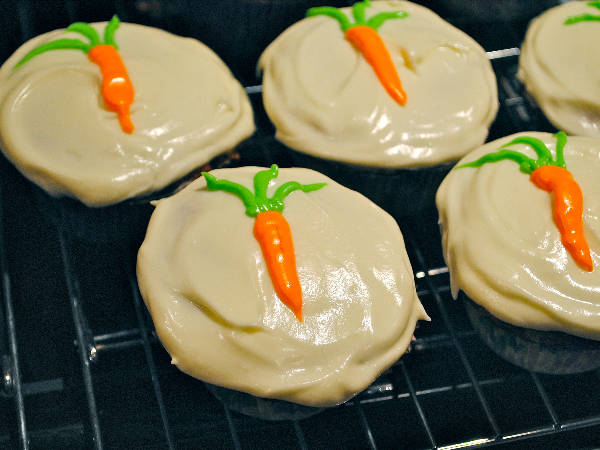 close up view of Carrot Pineapple Cupcakes garnished with icing on a cooling rack