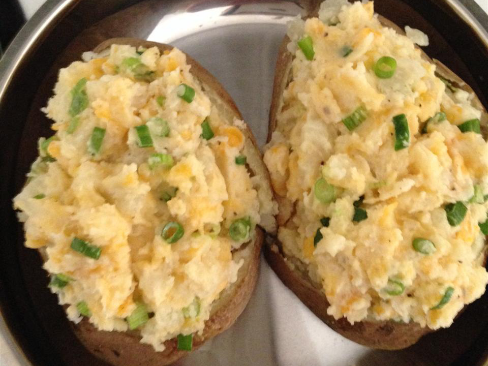 close up view of Stuffed Potatoes garnished with green onions on a plate