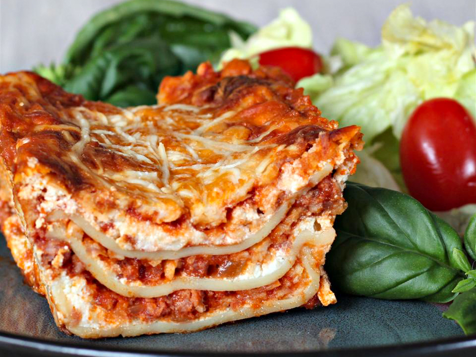 close up view of a slice of Italian Sausage Lasagna served with salad on a plate