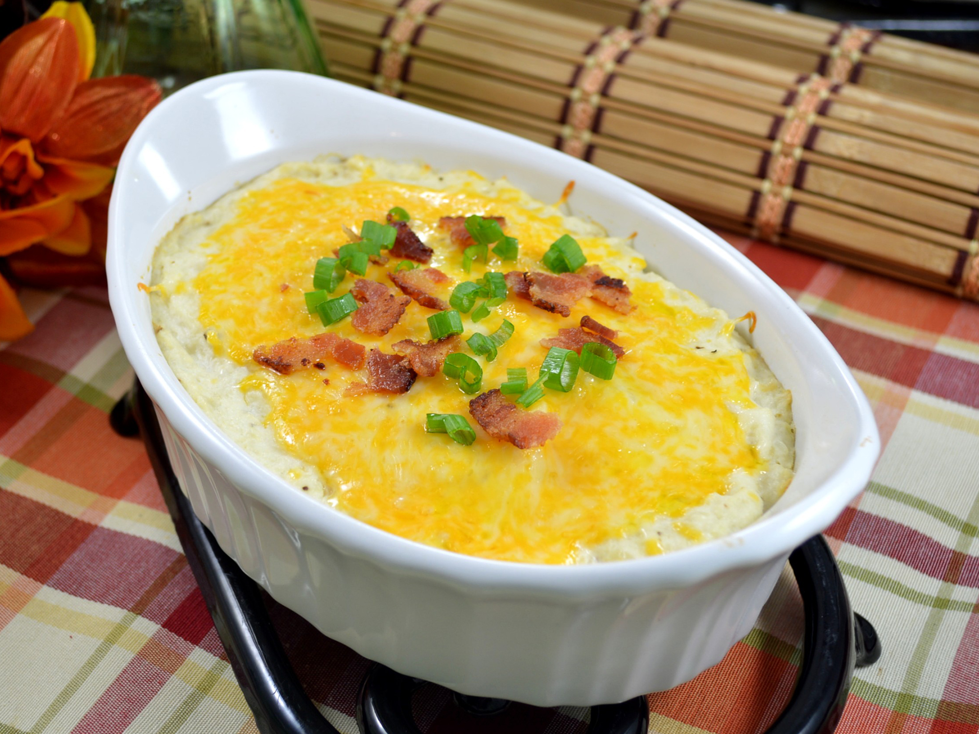 close up view of Mashed Cauliflower Bake garnished with bacon and green onions in a white baking dish