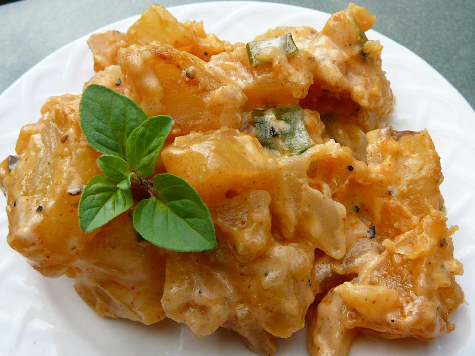 close up view of a Cheesy Ranch Potato Bake garnished with herbs on a white plate