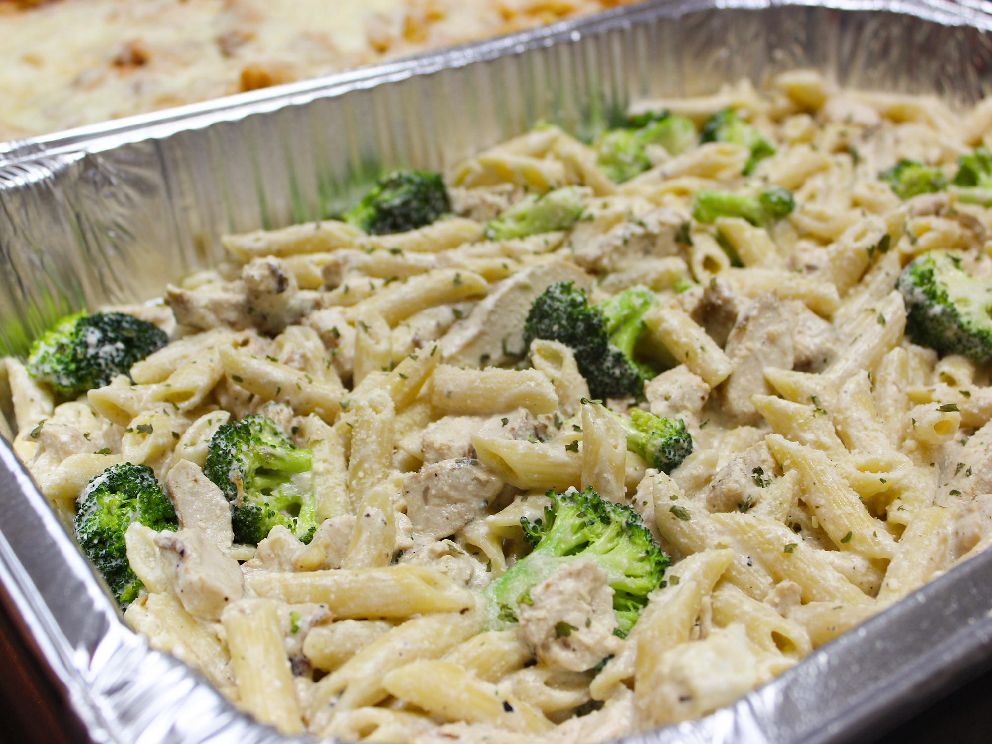 close up view of Baked Chicken Alfredo in an aluminum baking dish