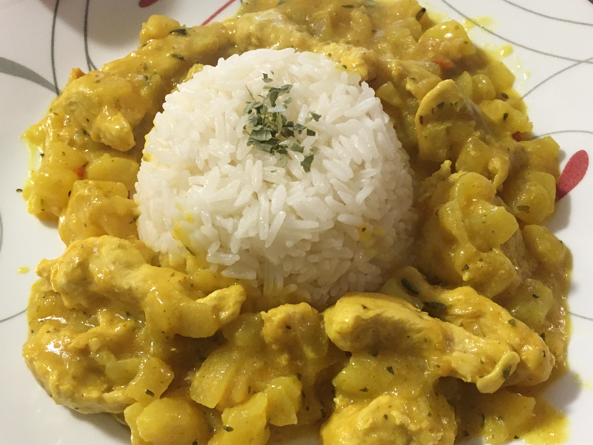 close up view of Curried Chicken surrounding white rice on a plate