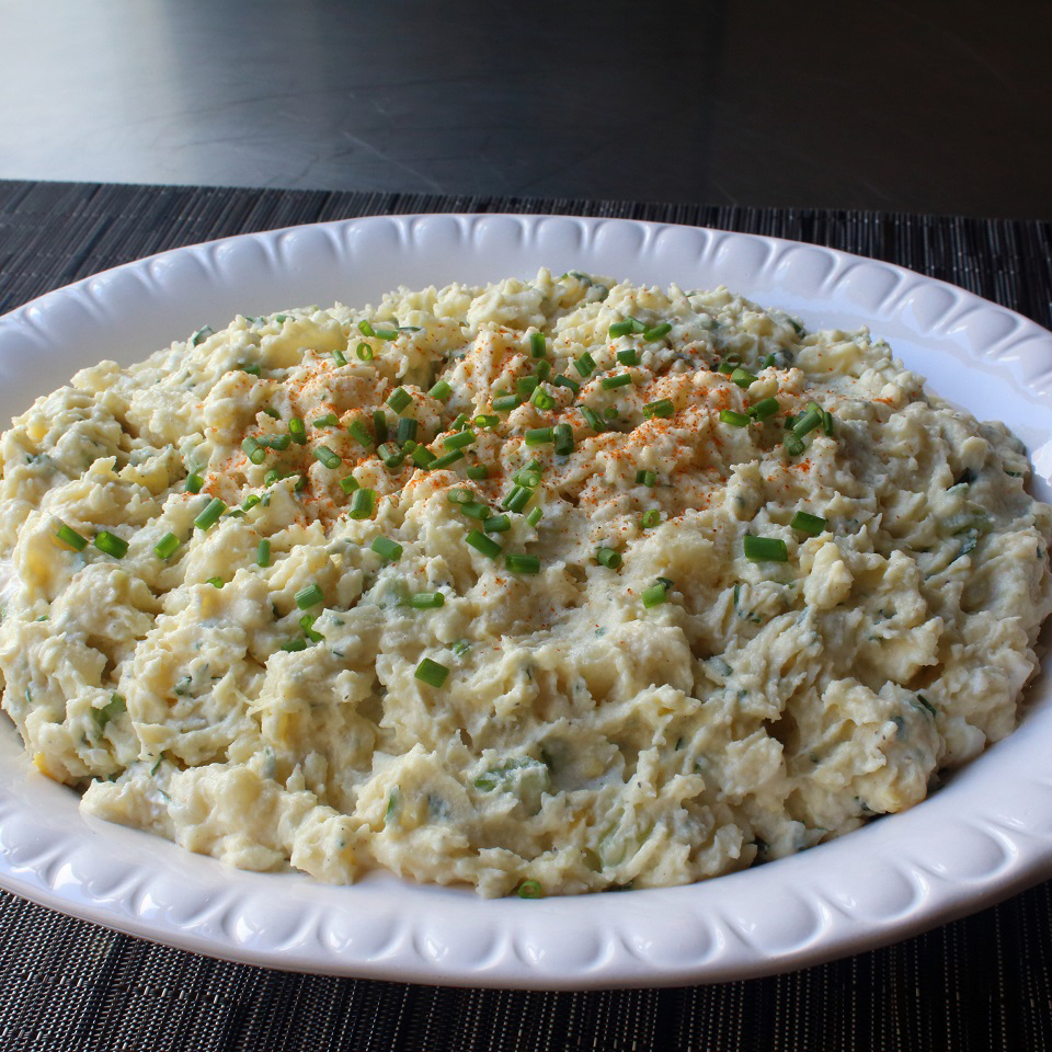 close up view of Potato Salad garnished with chives on a white platter