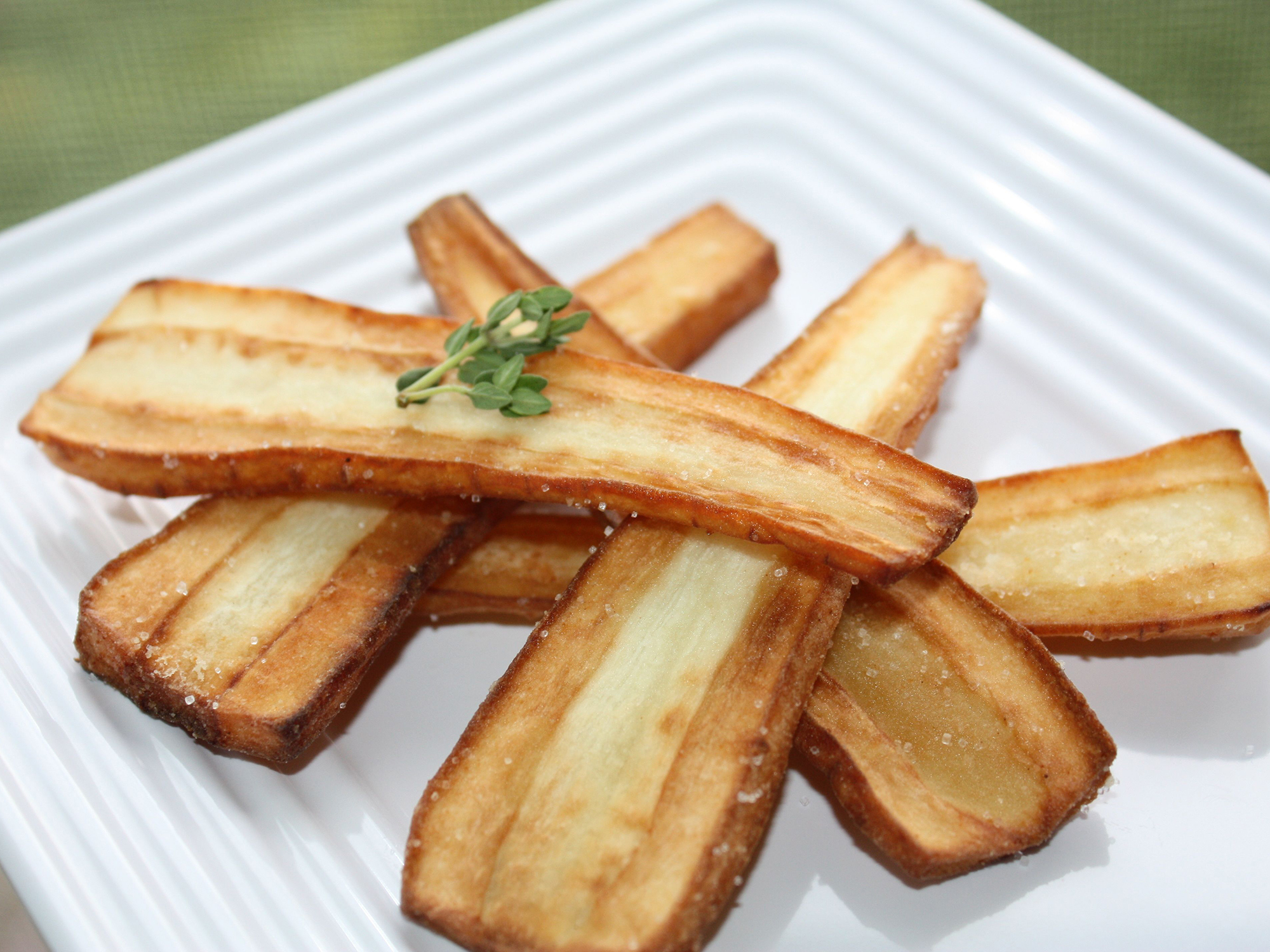 close up view of Butter Fried Parsnips garnished with fresh herbs on a white plate
