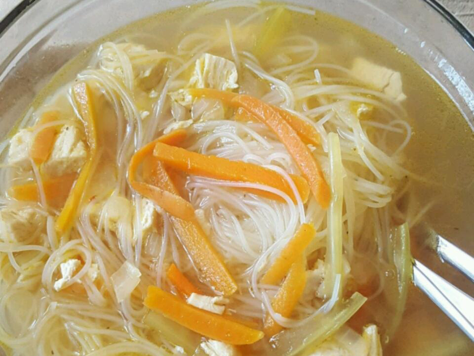 close up view of Shrimp Noodle Soup in a glass bowl with a spoon