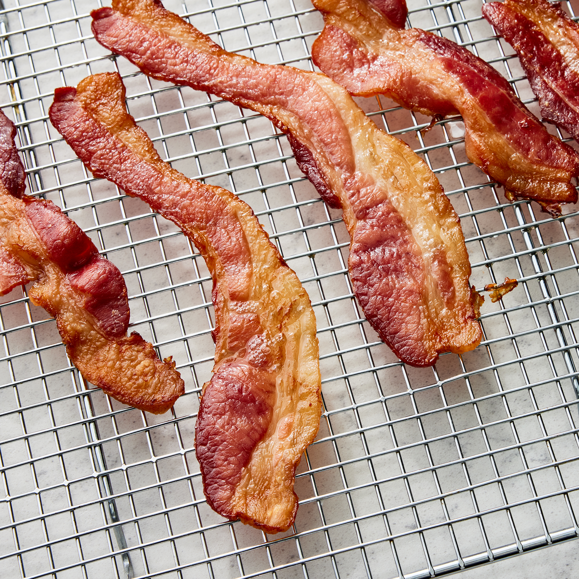 close up on a few pieces of oven-baked bacon resting on a cooling rack
