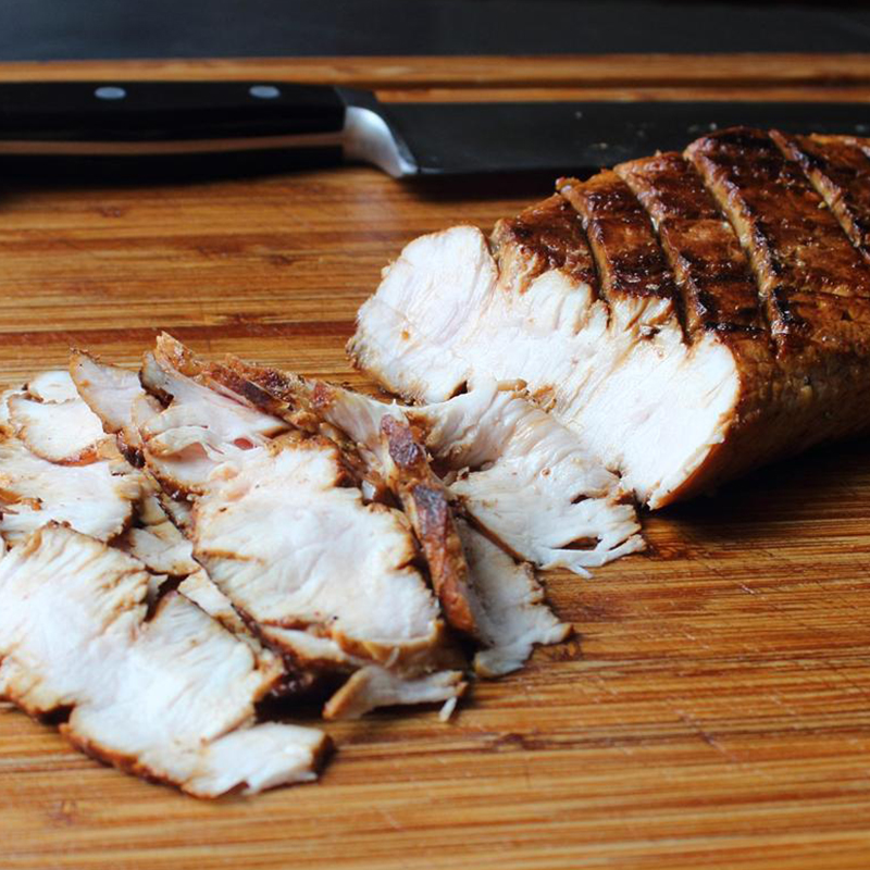 close up view of a sliced Pan-Roasted 5-Spice Pork Loin on a cutting board with a knife