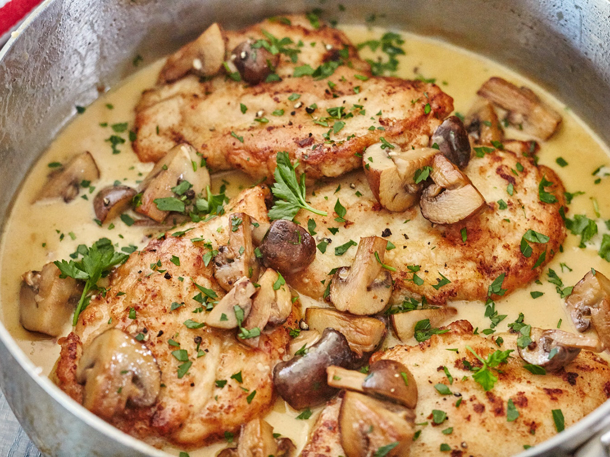 close up view of Chicken Marsala with mushrooms, garnished with fresh herbs in a pot