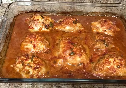 a glass baking dish of chicken thighs in a cranberry onion sauce