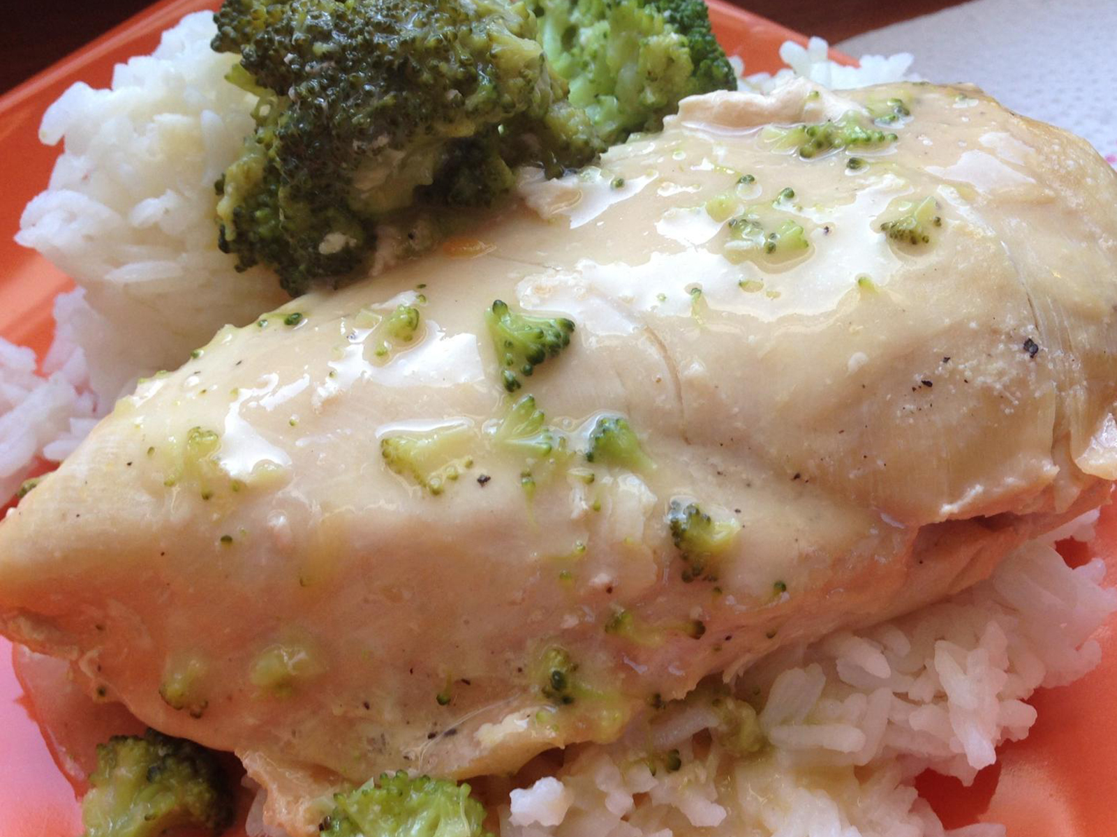 close up view of Slow Cooker Dump and Go Cheesy Chicken with broccoli and rice on a red plate