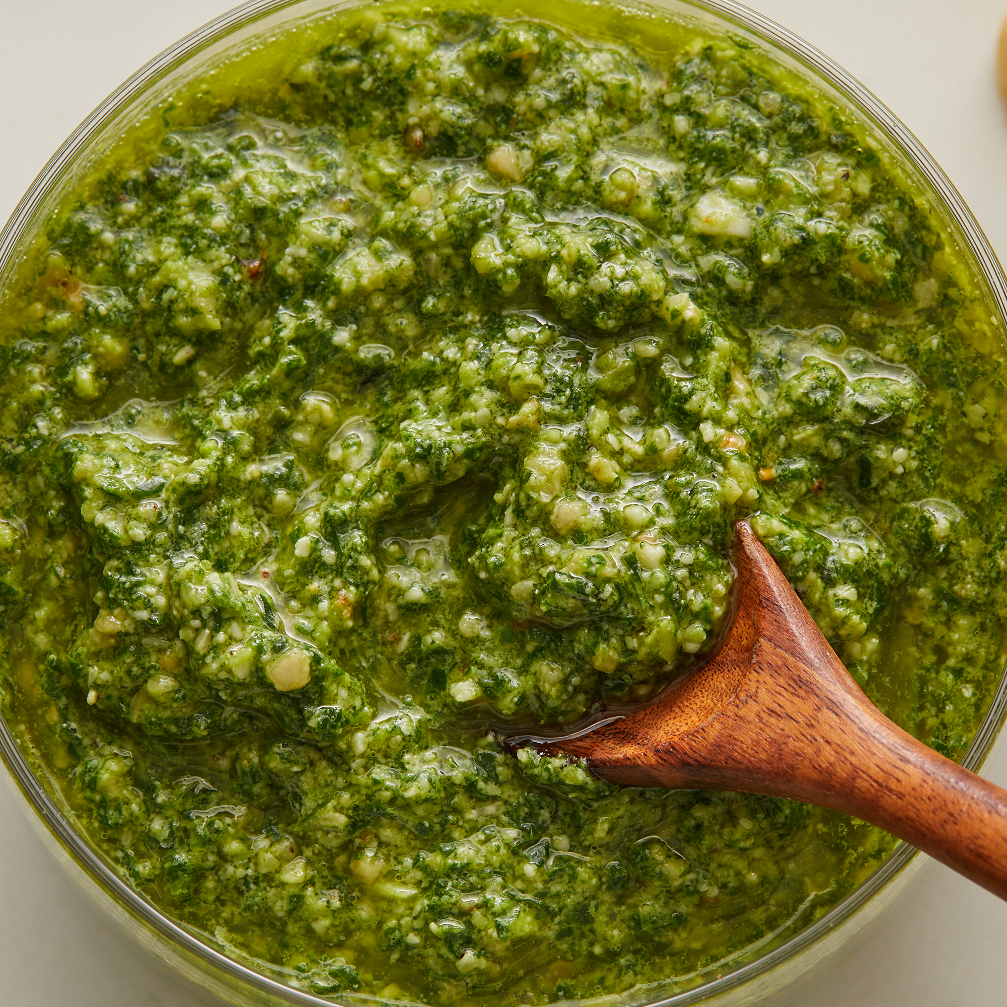 looking down at a bowl of spinach basil pesto with a spoonful resting on top