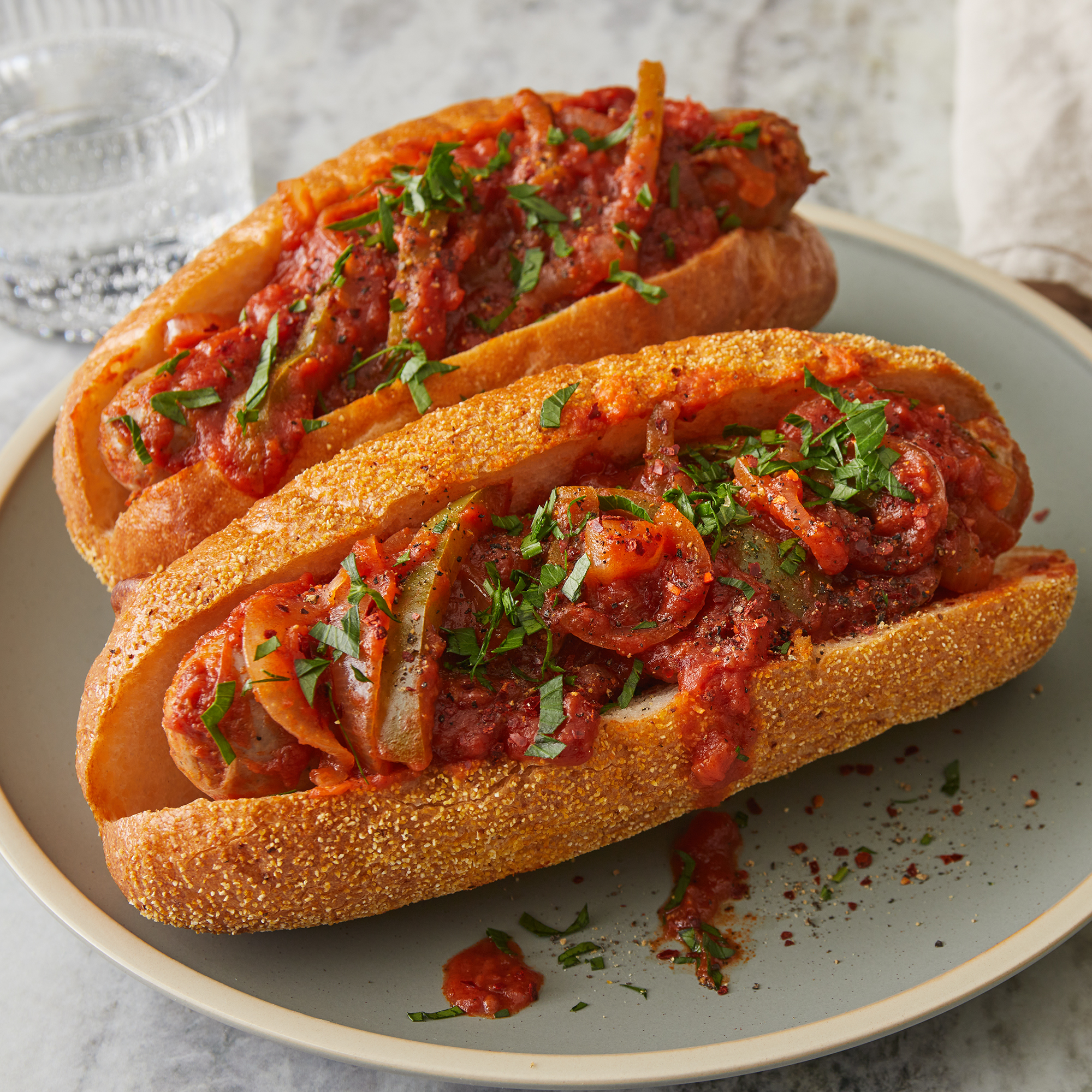 Close up on two slow cooker sausages on hoagies with sauce