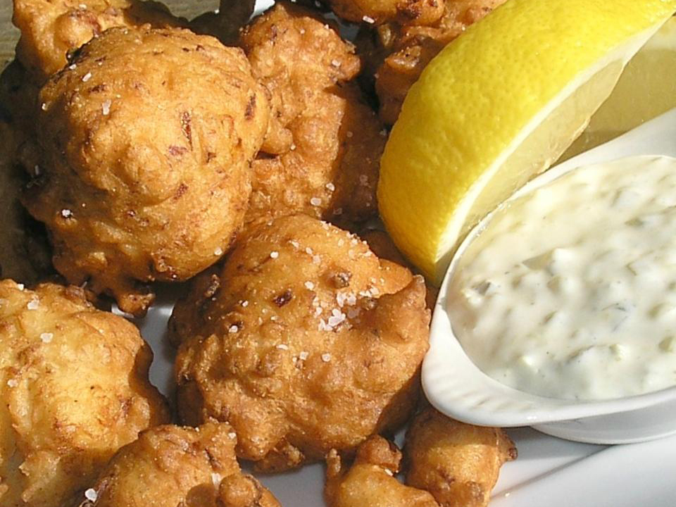 close up view of Clam Fritters with white sauce and lemon wedges on a plate