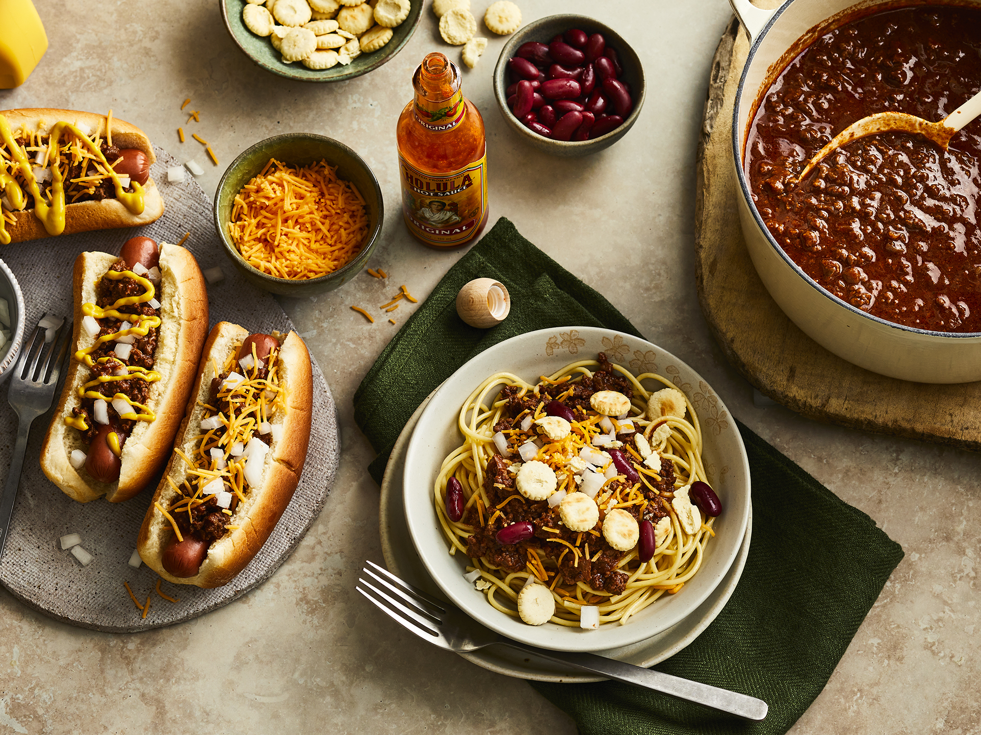 close up view of Cincinnati Chili over pasta in a bowl, on hot dogs and in a pot