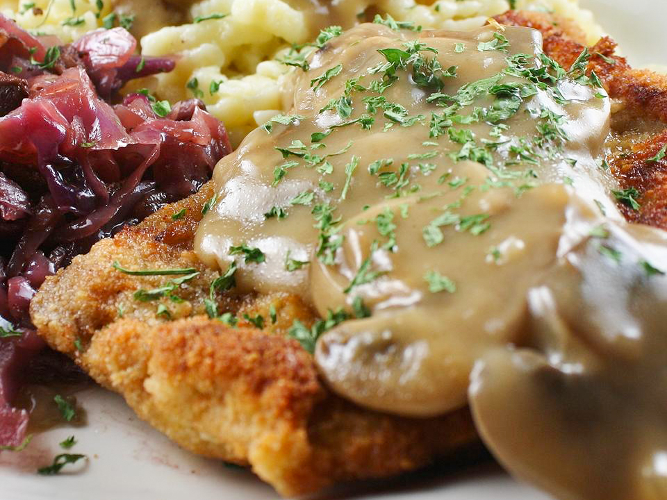close up view of Jaeger Schnitzel served with gravy and red cabbage on a plate