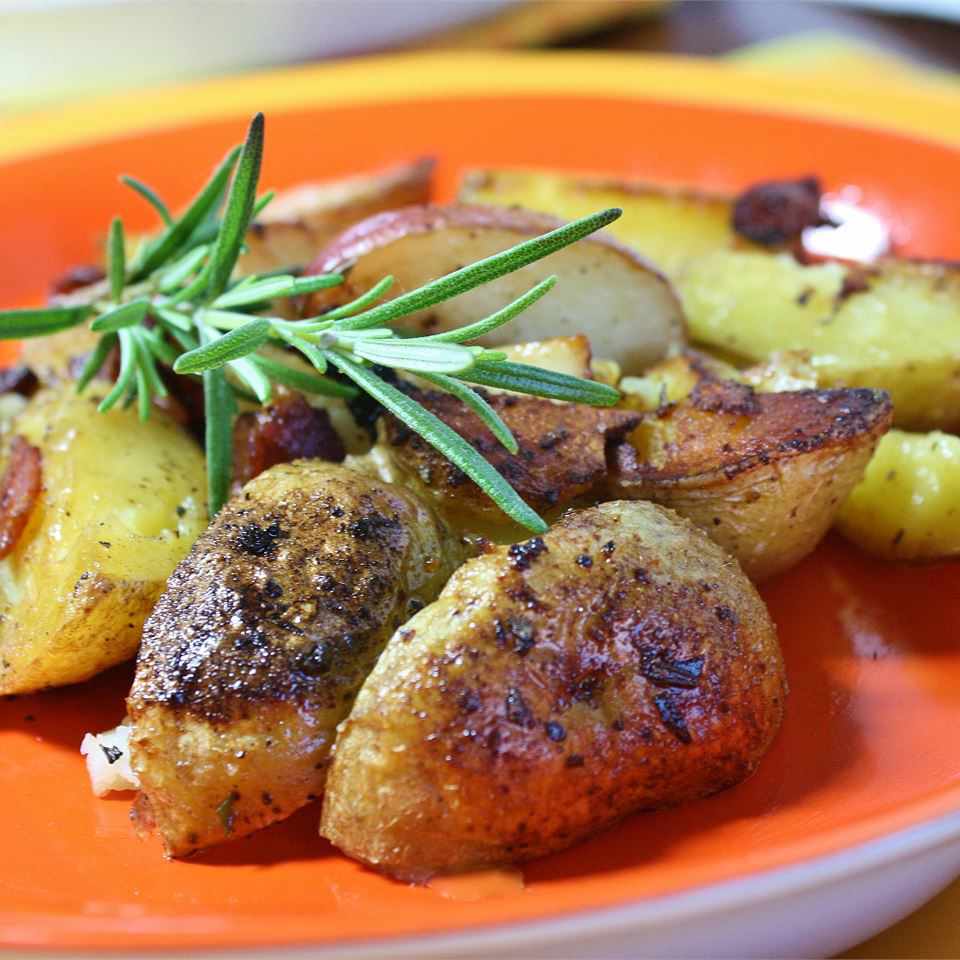 close up view of Pan-Roasted Marble Potatoes garnished with fresh herbs on an orange and yellow plate