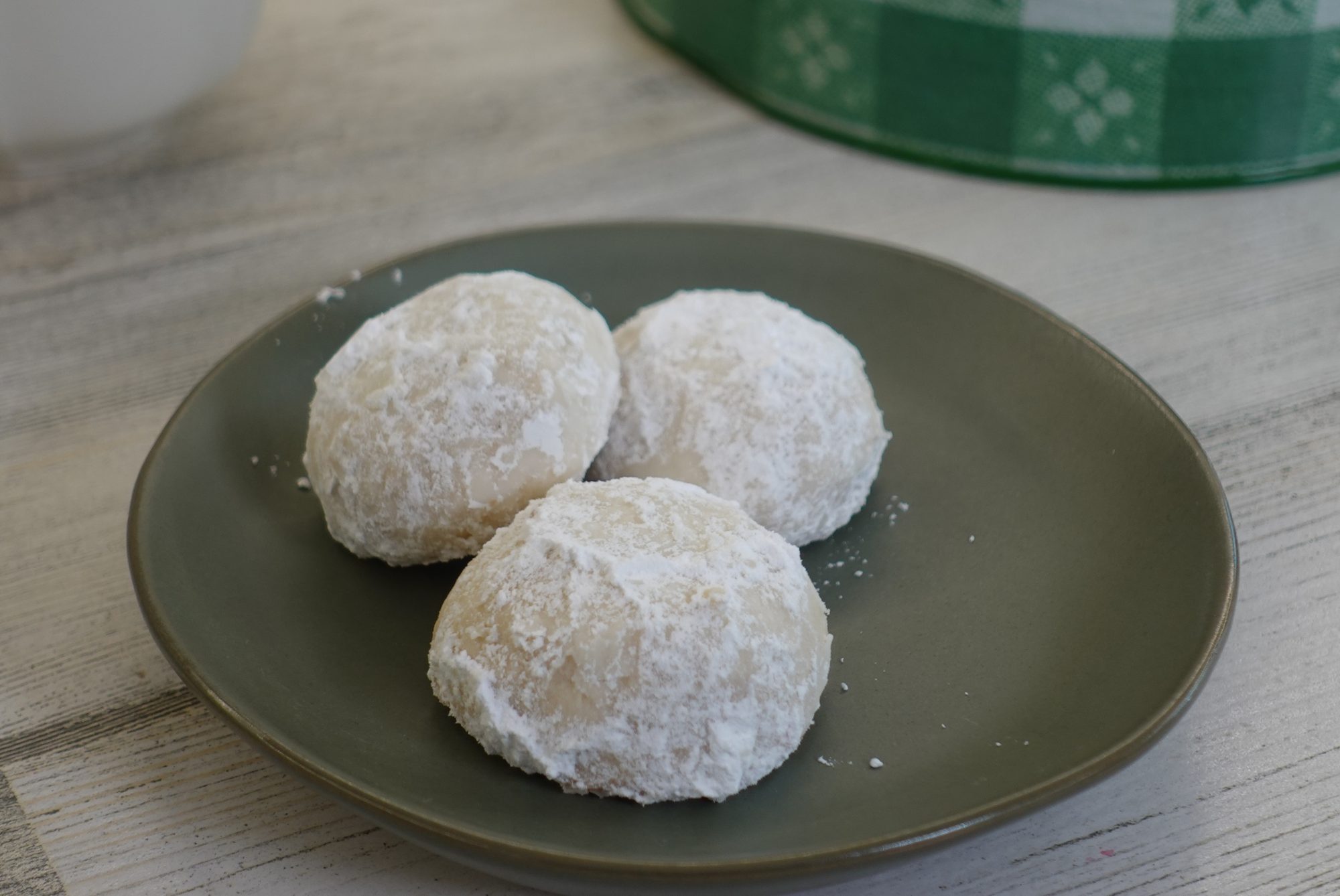 three round powdered sugar-dusted cookies on a plate